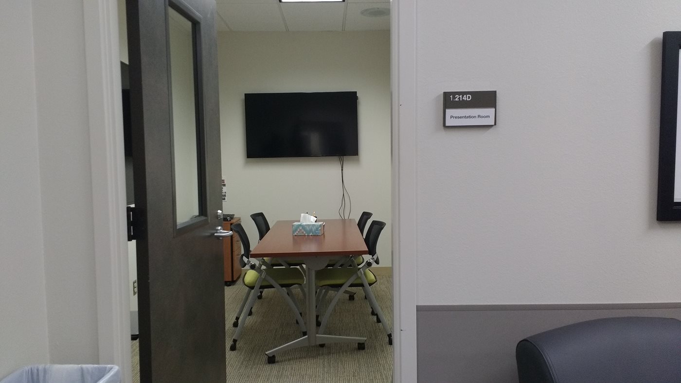 Looking through an open door into a small conference room area with a TV on the far wall